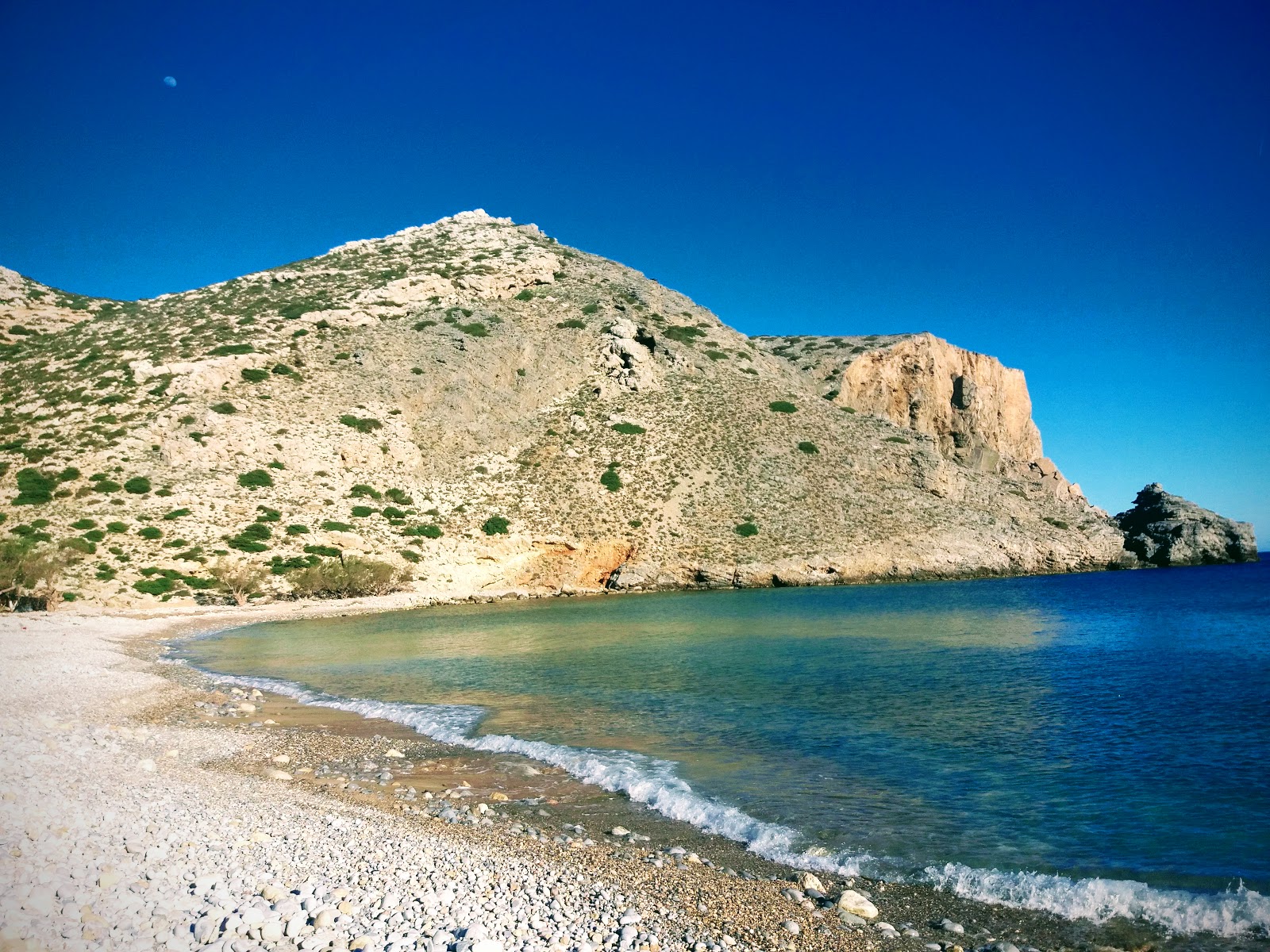 Foto van Helatros Beach Kasos Greece met zand met kiezelstenen oppervlakte
