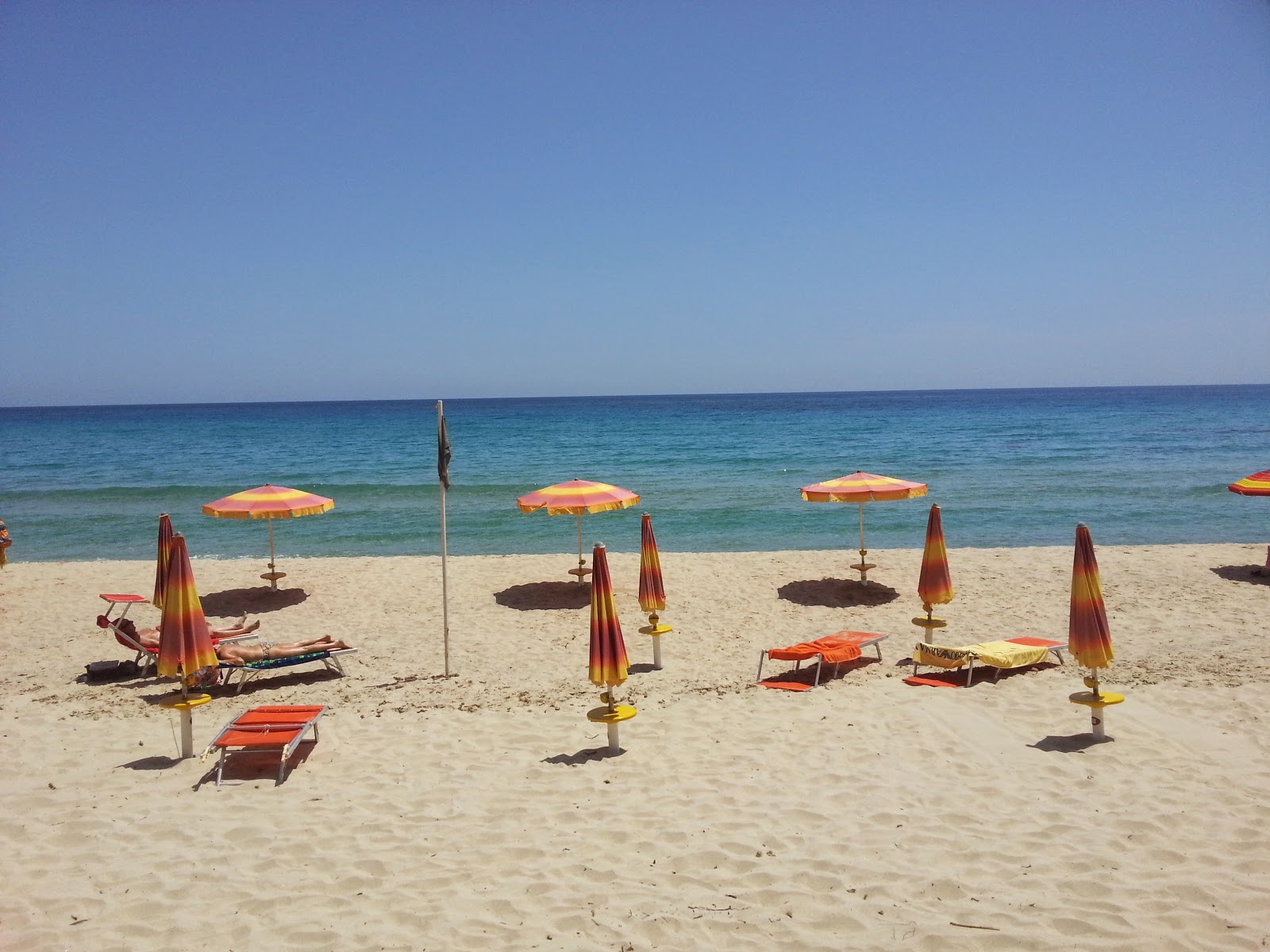 Foto av Santa Giusta Stranden med blå rent vatten yta