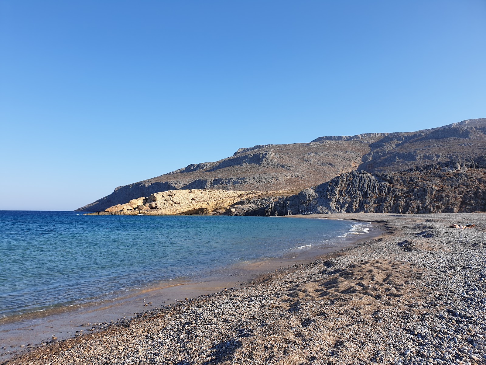 Fotografie cu Karoumes beach cu o suprafață de nisip gri și pietricel