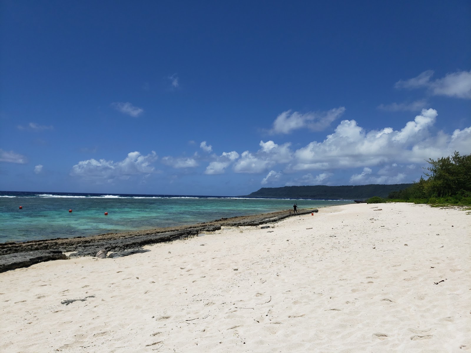 Foto van Tarague Beach met helder zand & rotsen oppervlakte