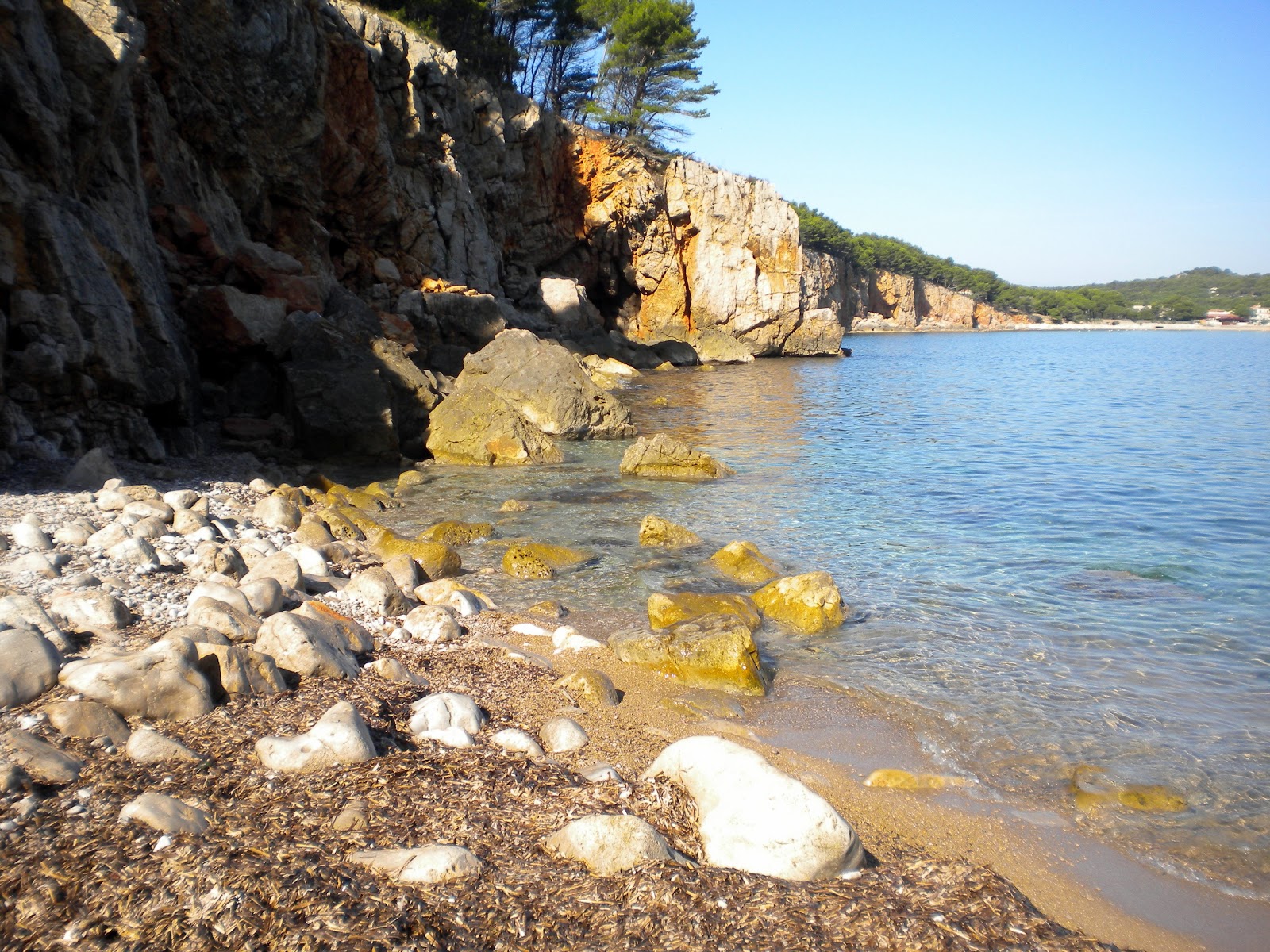 Photo of Cala Donzell with bright sand & rocks surface