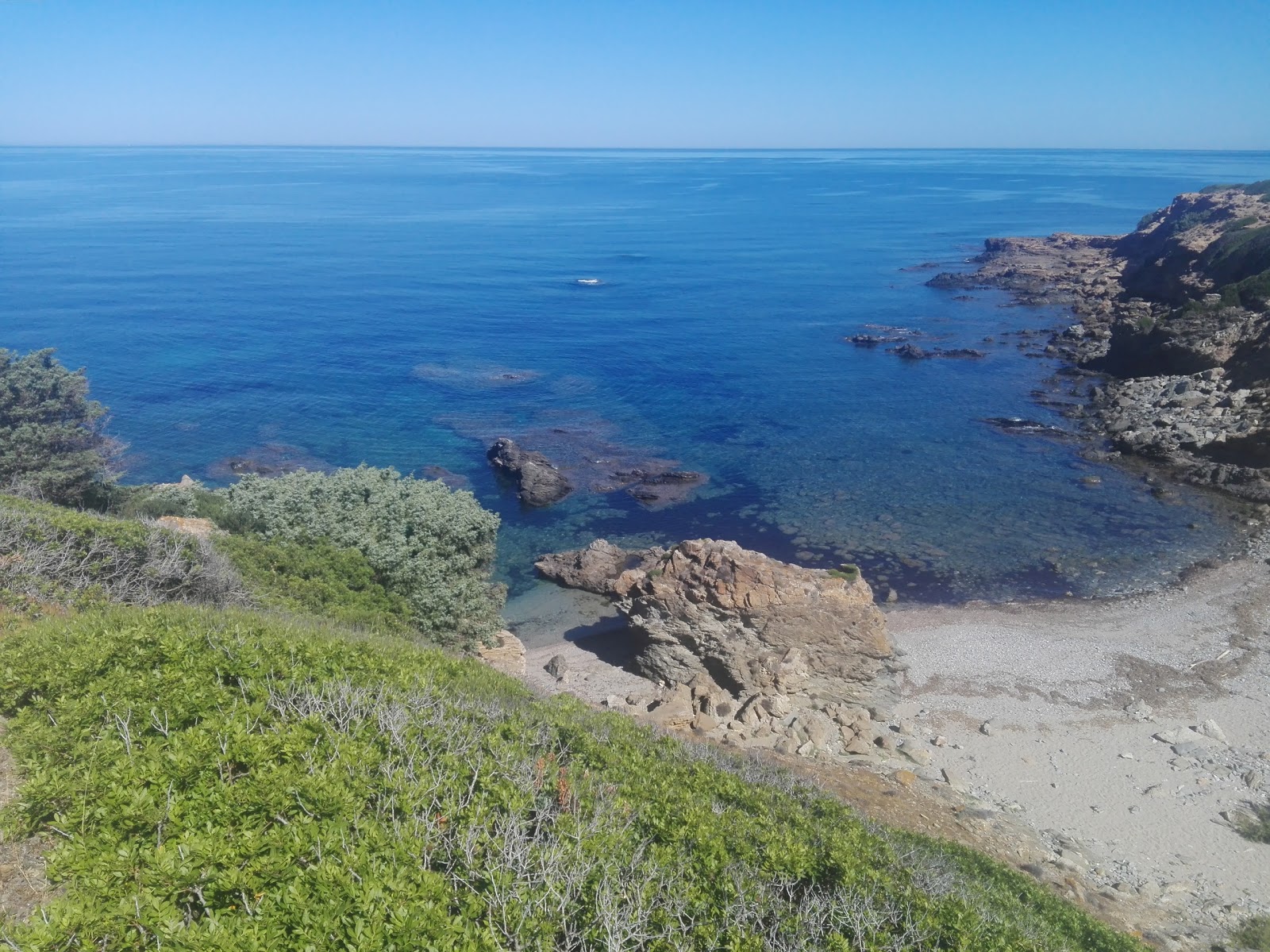Valokuva Spiaggia di Punta Campu Saliista. pinnalla harmaa hiekka ja kivet:n kanssa