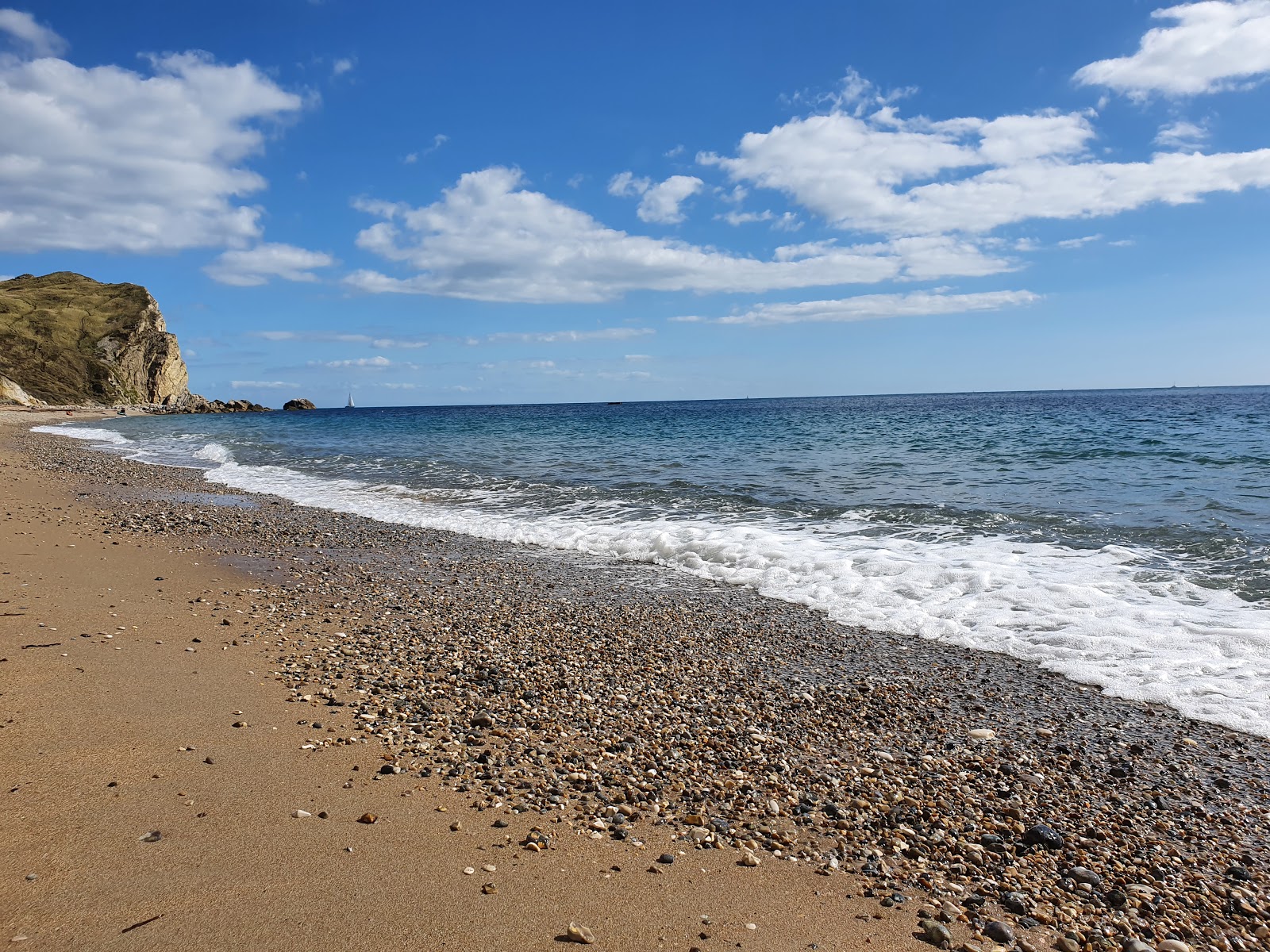Fotografie cu St Oswald's Bay beach cu o suprafață de apă pură albastră