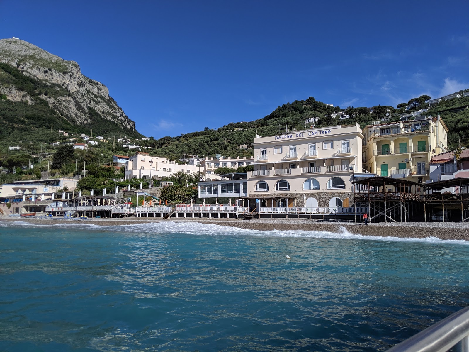 Foto af Nerano Strand bakket op af klipperne