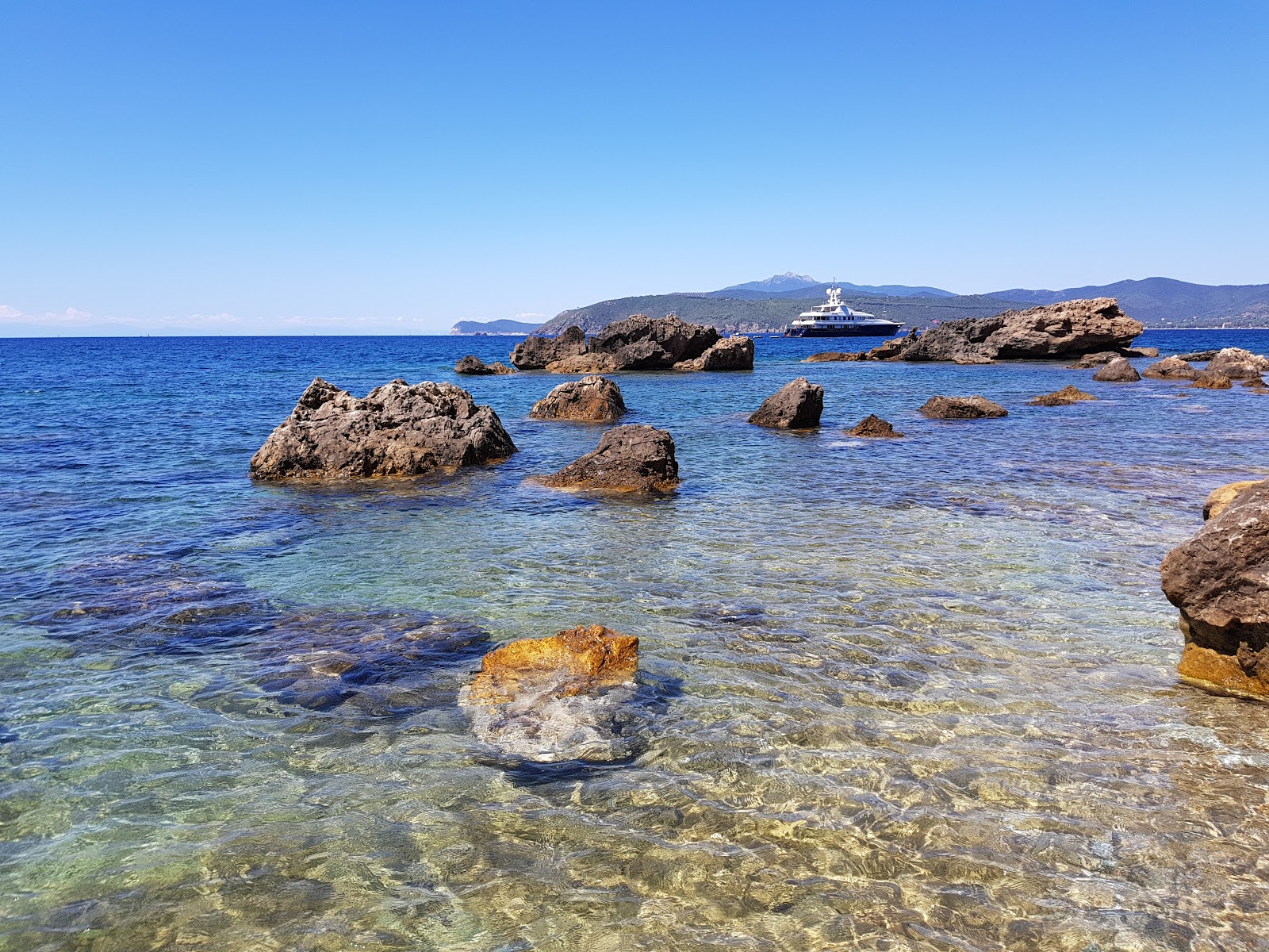 Peducelli beach'in fotoğrafı turkuaz saf su yüzey ile