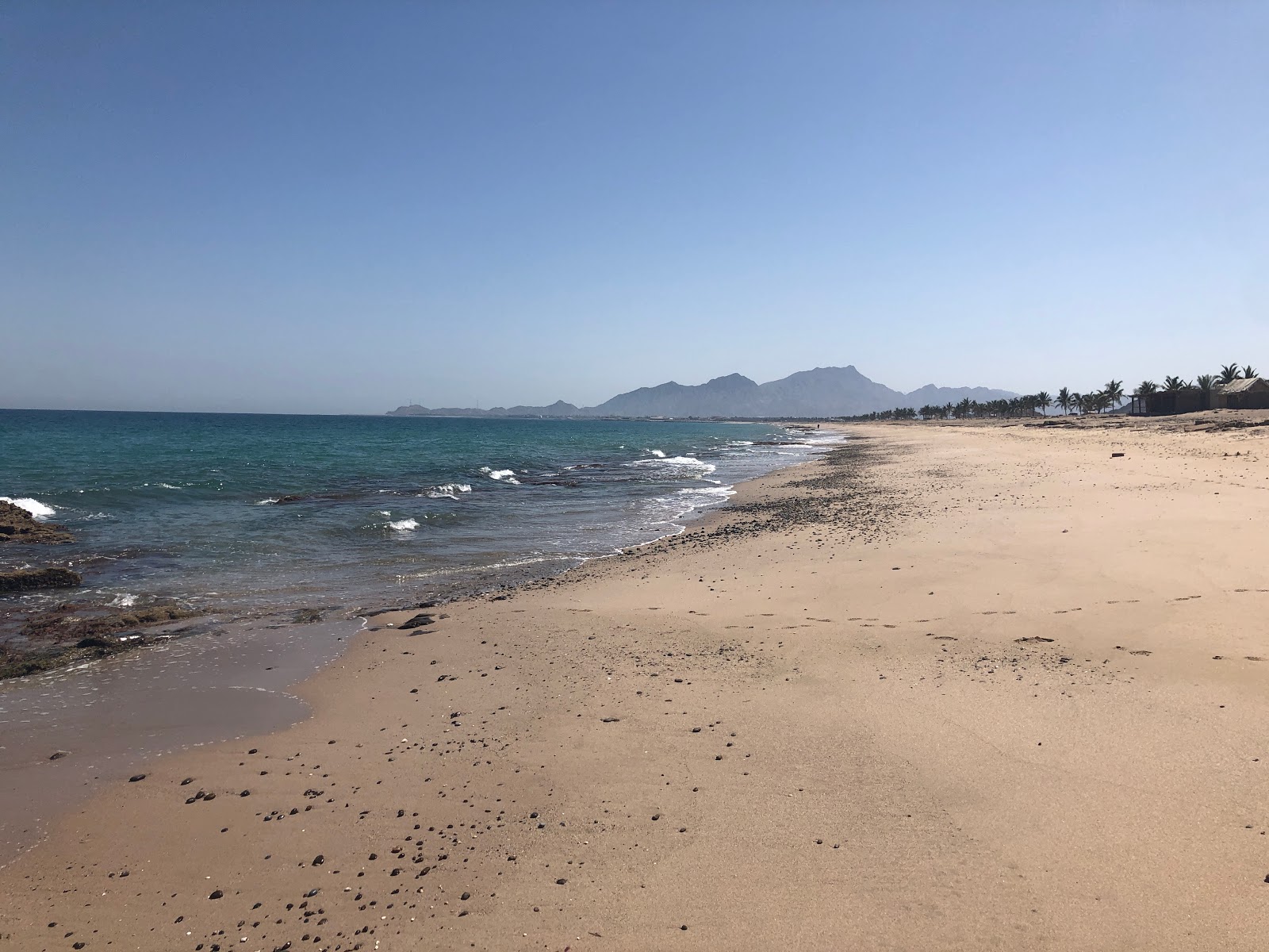 Foto de Faqiat beach com areia bege e seixos superfície
