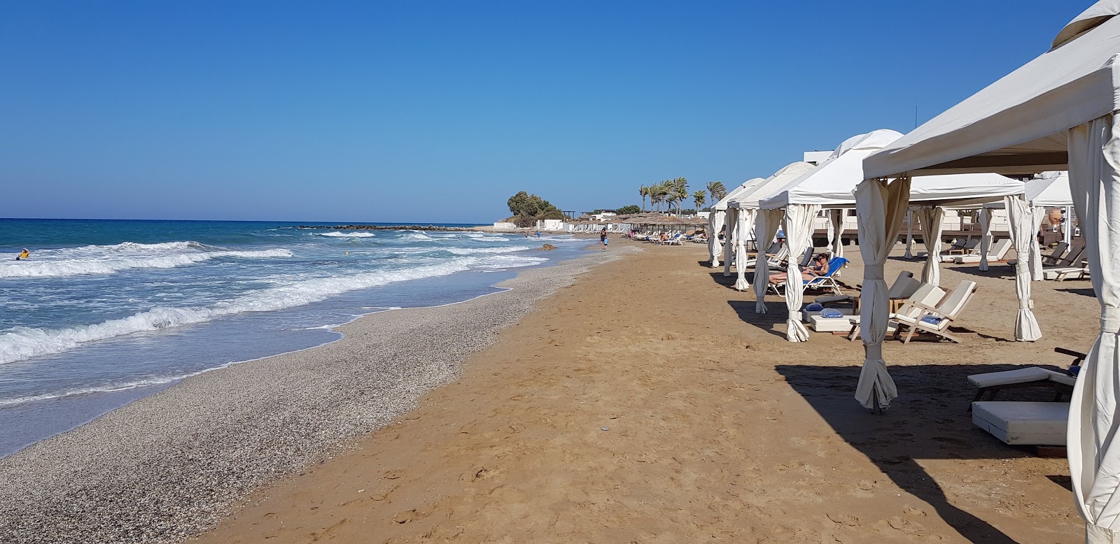 Valokuva Agios Pelagia beachista. pinnalla ruskea hiekka:n kanssa