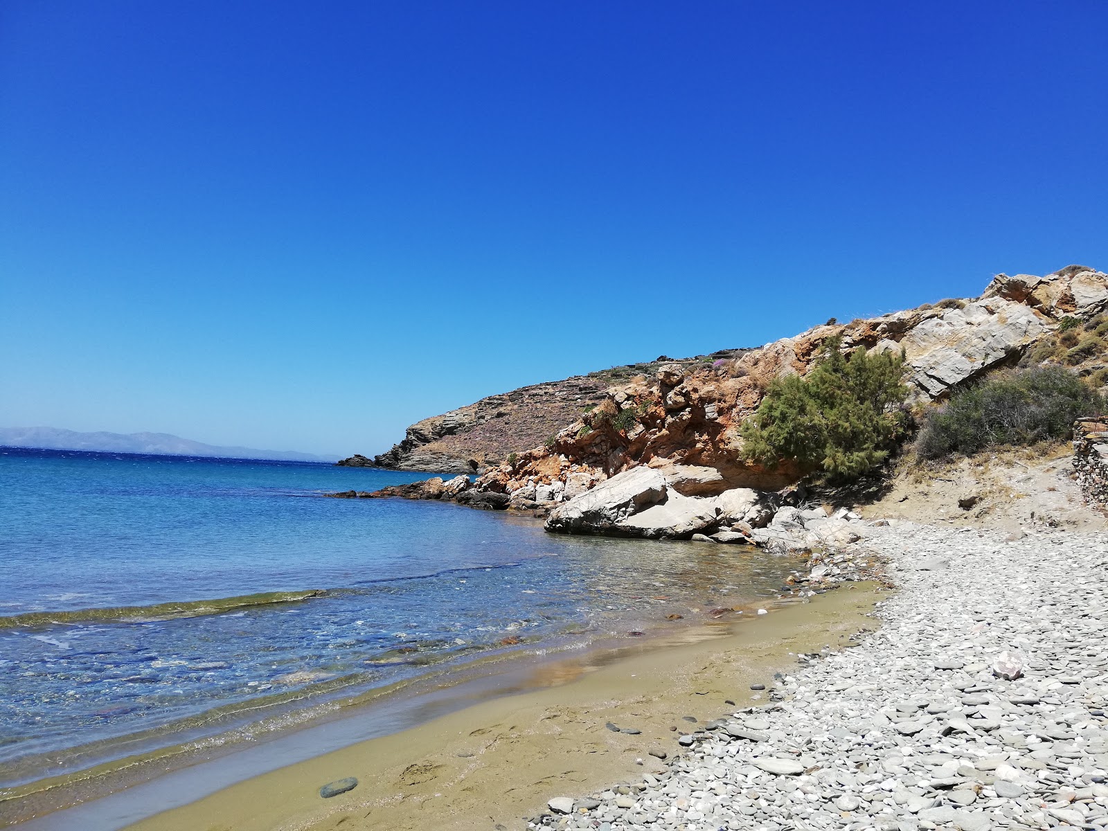 Foto af Agios Petros beach bakket op af klipperne
