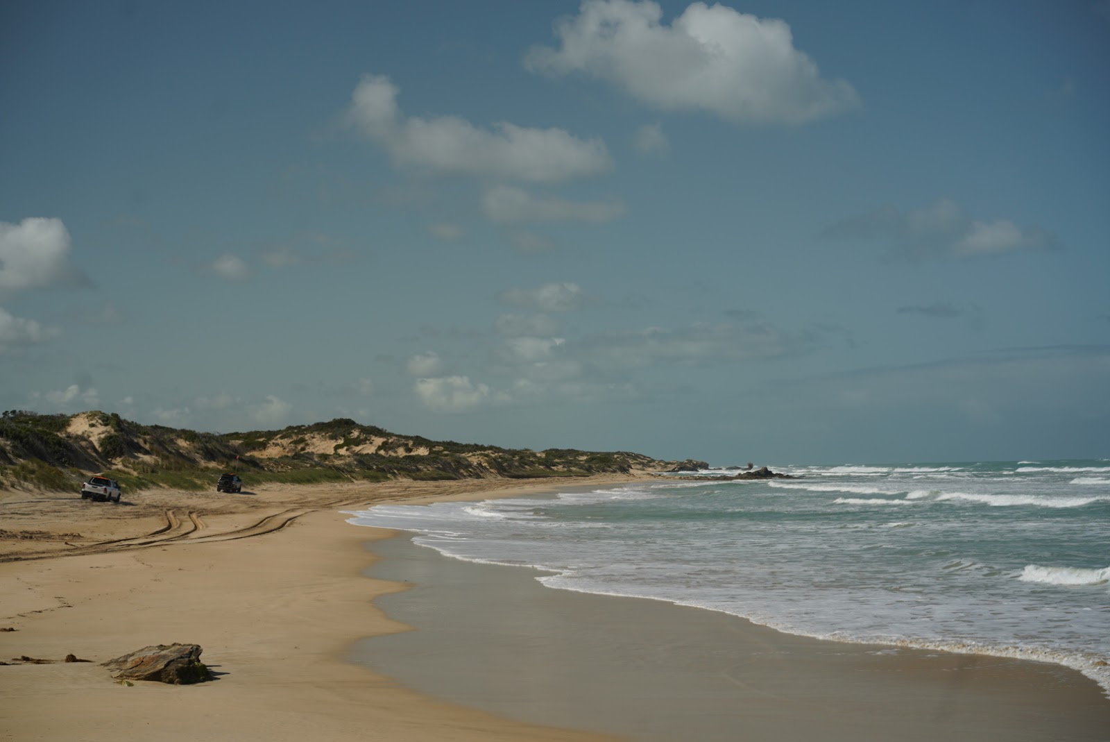 Fotografija Back Beach z svetel pesek površino