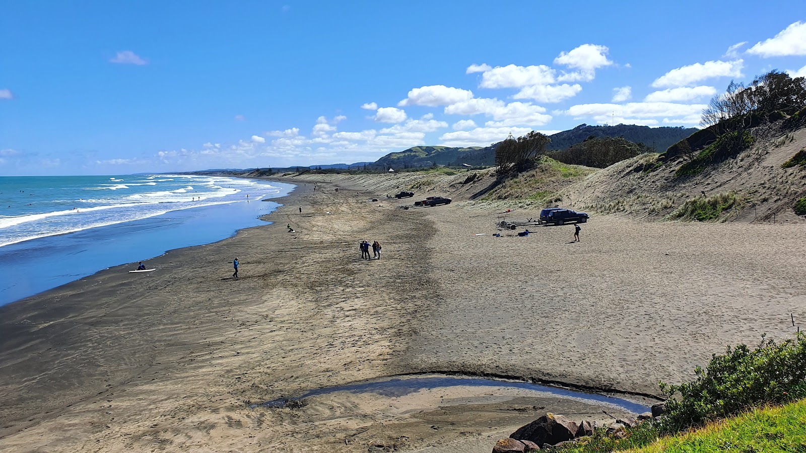 Foto av Muriwai Beach omgiven av klippor
