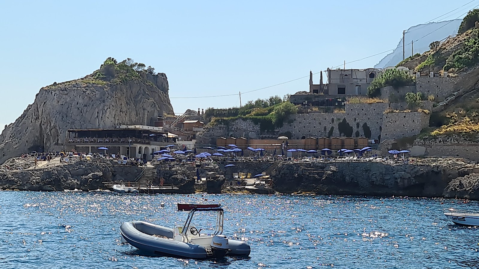 Fotografija Spiaggia Da Luigi Ai Faraglioni obkrožen z gorami