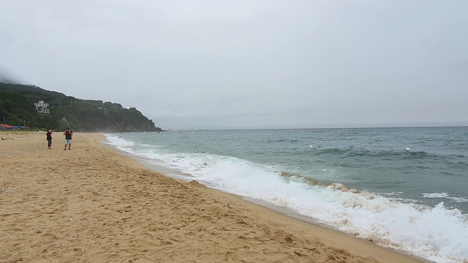 Foto av Deungmyeong Beach omgiven av klippor