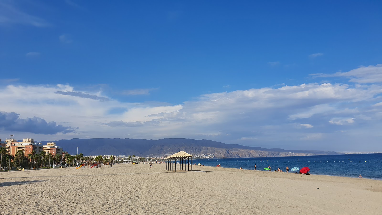 Foto di Playa de la Romanilla con una superficie del sabbia di conchiglie grigia