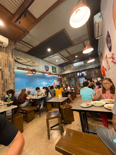 A busy restaurant with people dining at wooden tables, colorful wall decor, and warm lighting.