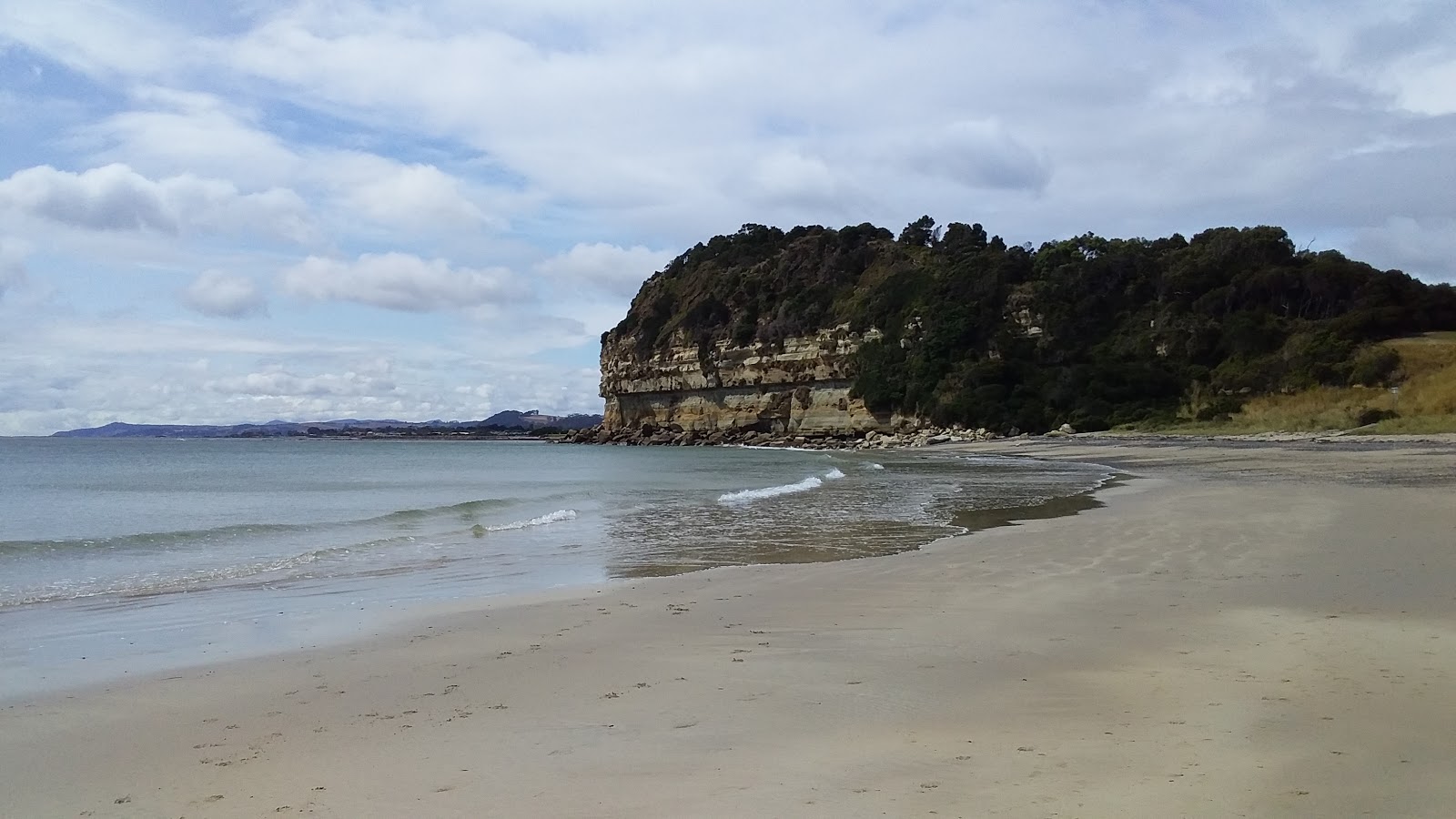 Foto di Fossil Bluff Beach con una superficie del sabbia luminosa e rocce