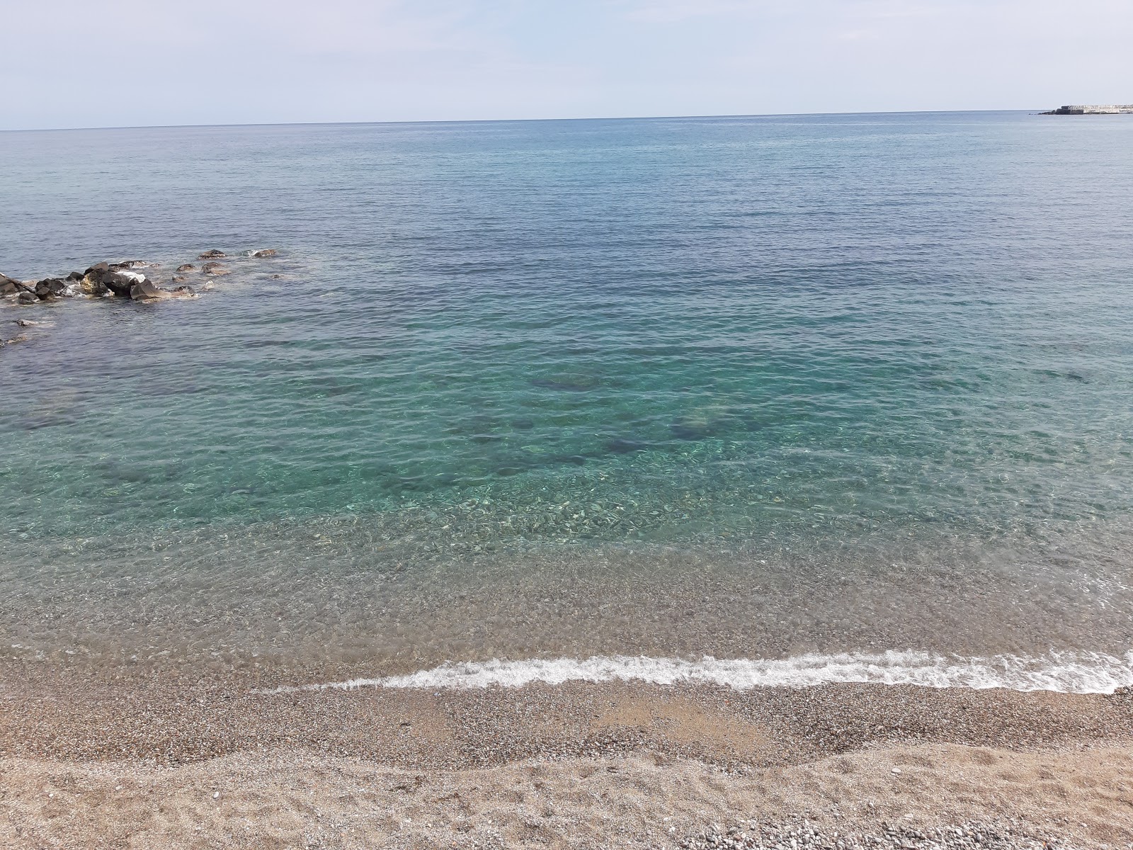 Foto van Spiaggia Giardini Naxos ondersteund door kliffen