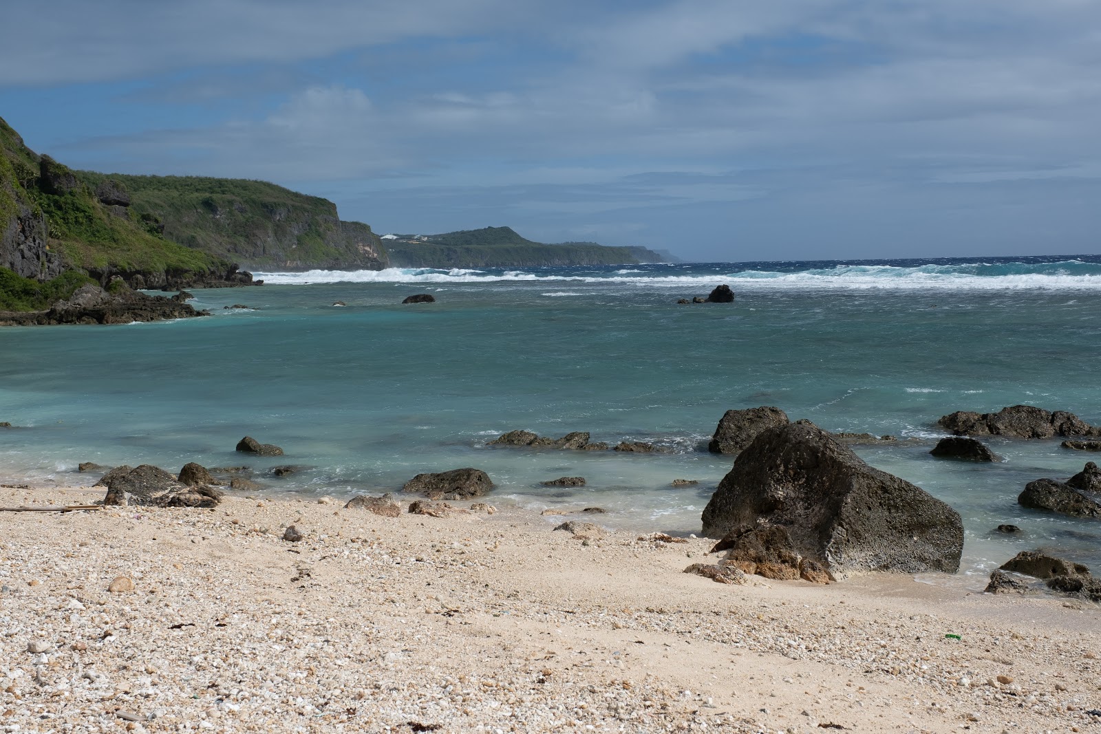 Taga'chang Beach的照片 带有明亮的沙子和岩石表面