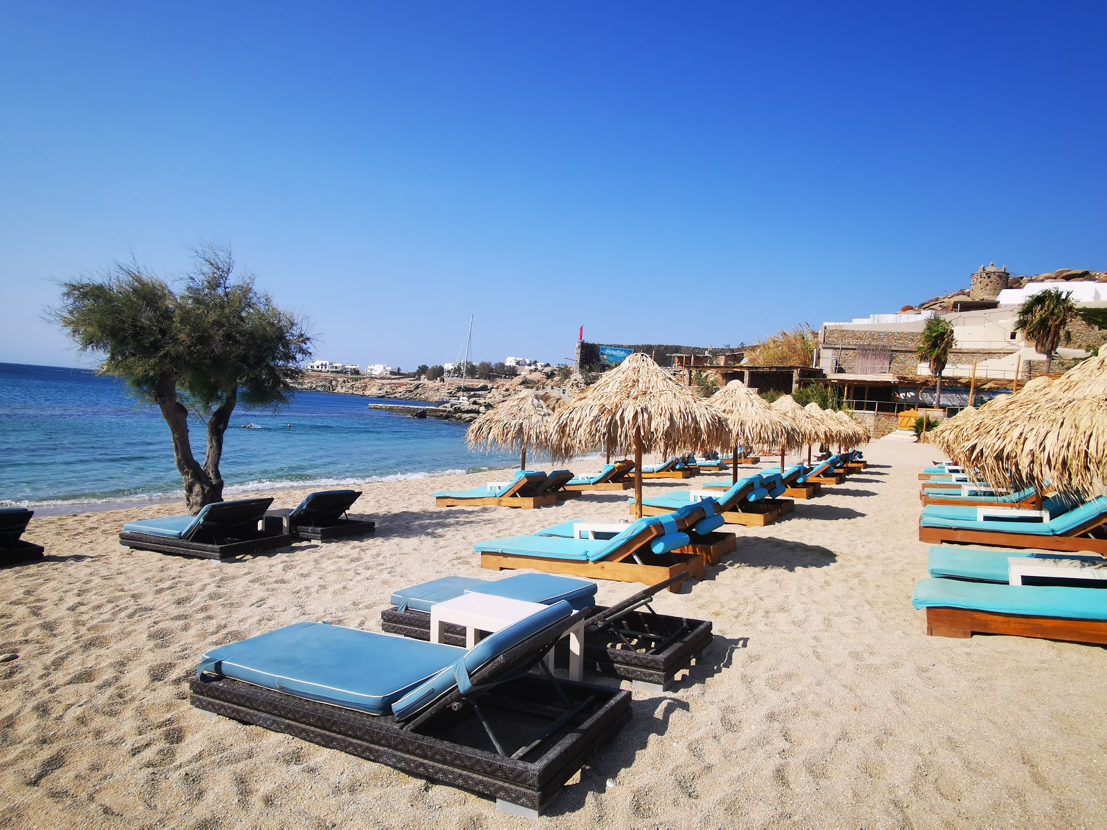 Super Paradise Beach remplie de transats et de parasols, avec des baigneurs se relaxant et profitant de la mer claire.