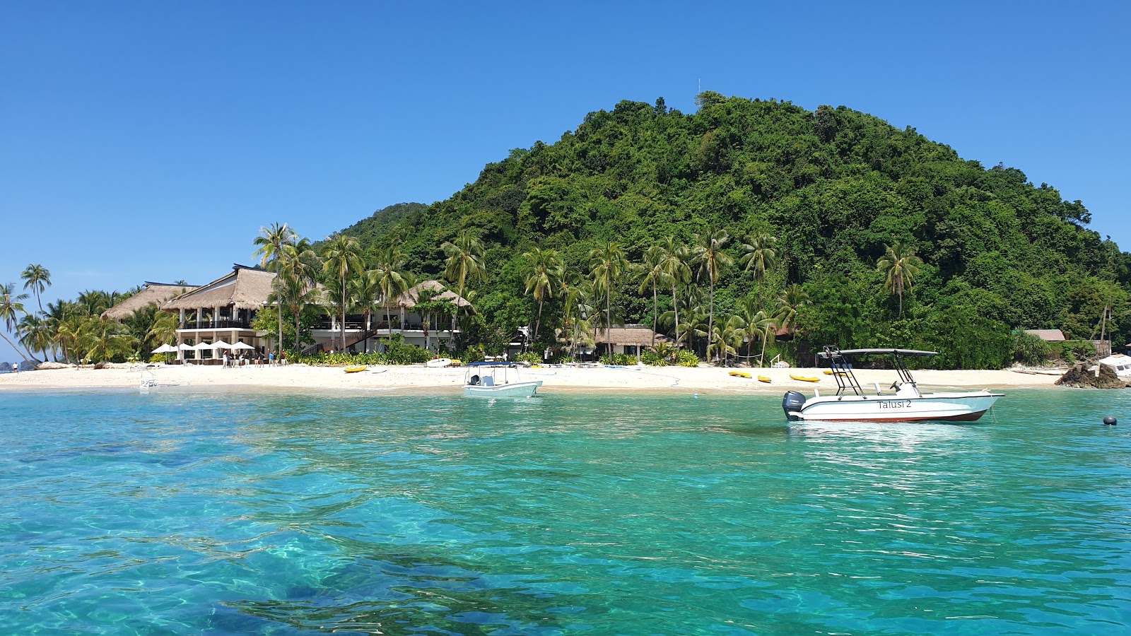 Foto von Pangulasian Island Strand von Klippen umgeben