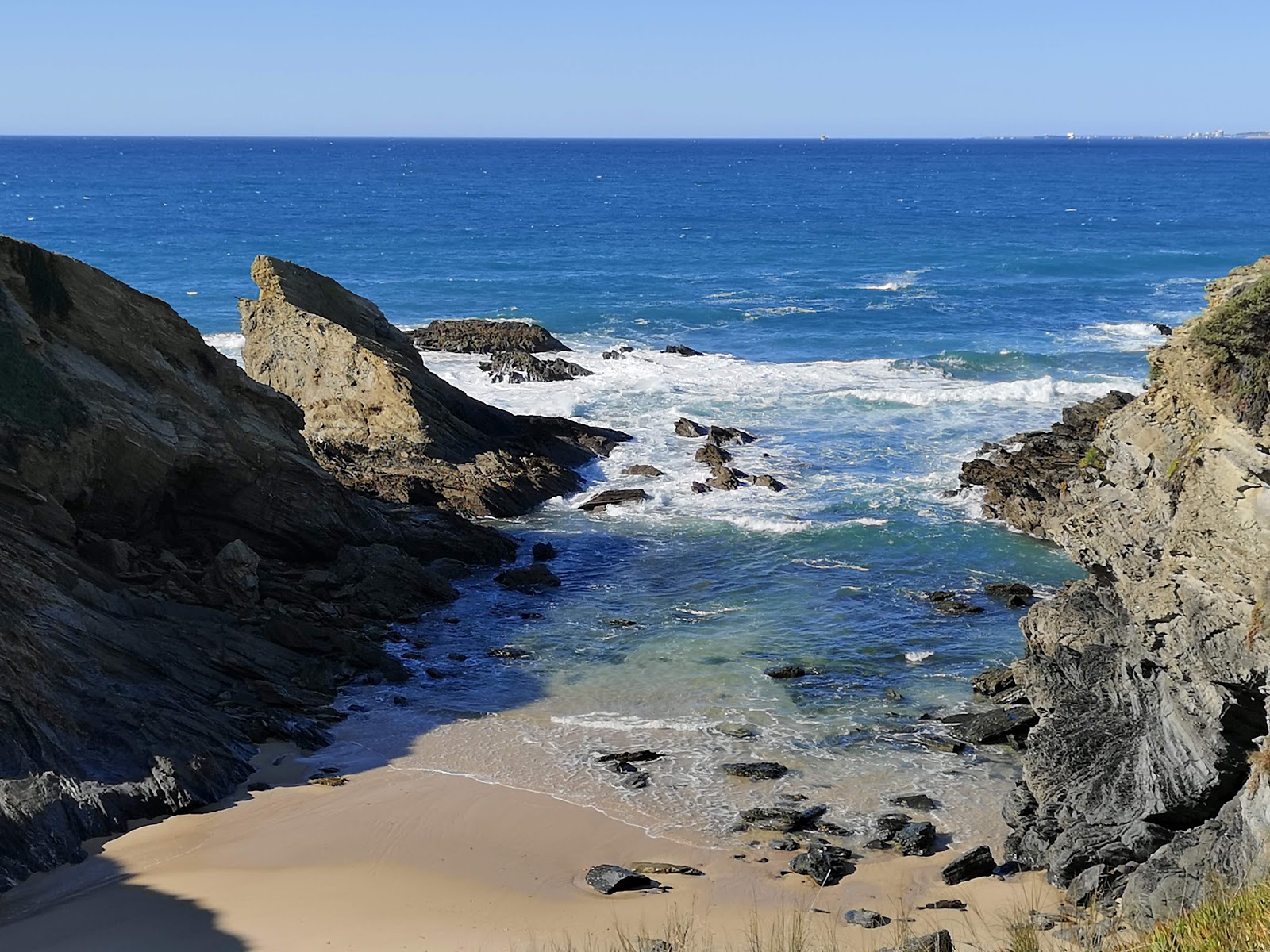 Valokuva Praia de Porto Covinhoista. pinnalla kirkas hieno hiekka:n kanssa