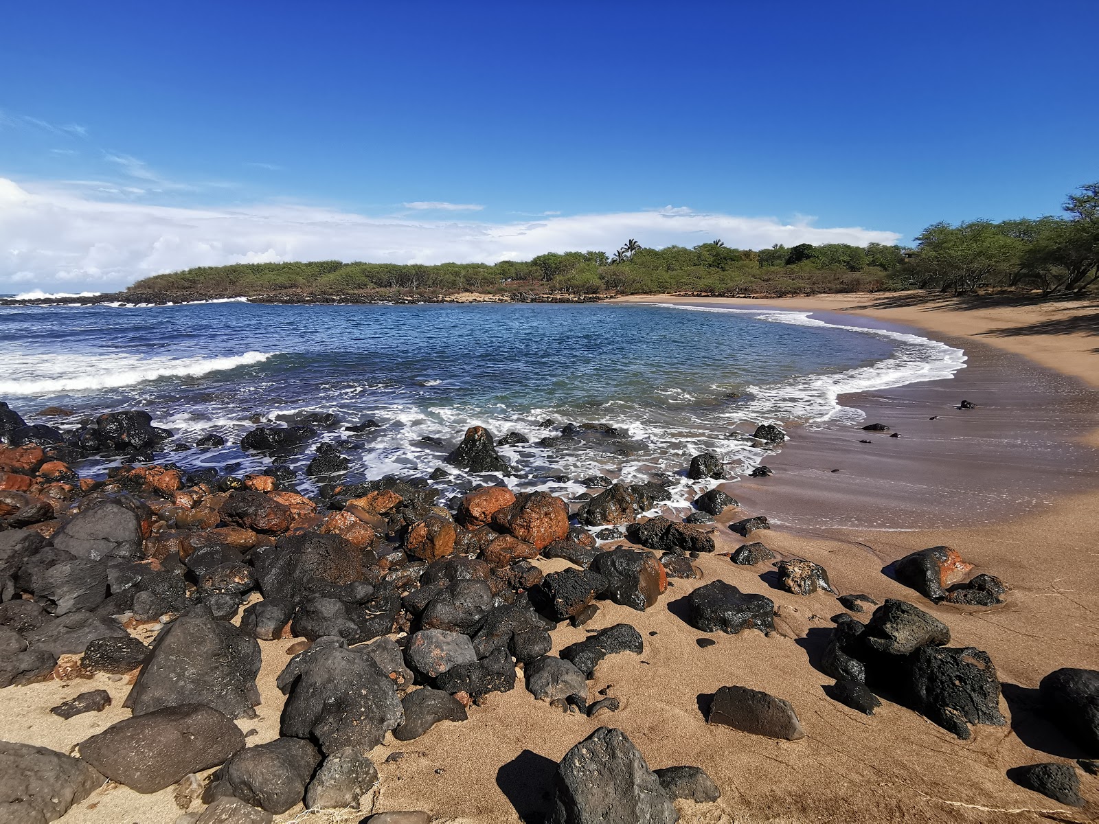 Photo of Kapukahehu Beach with dark blue water surface