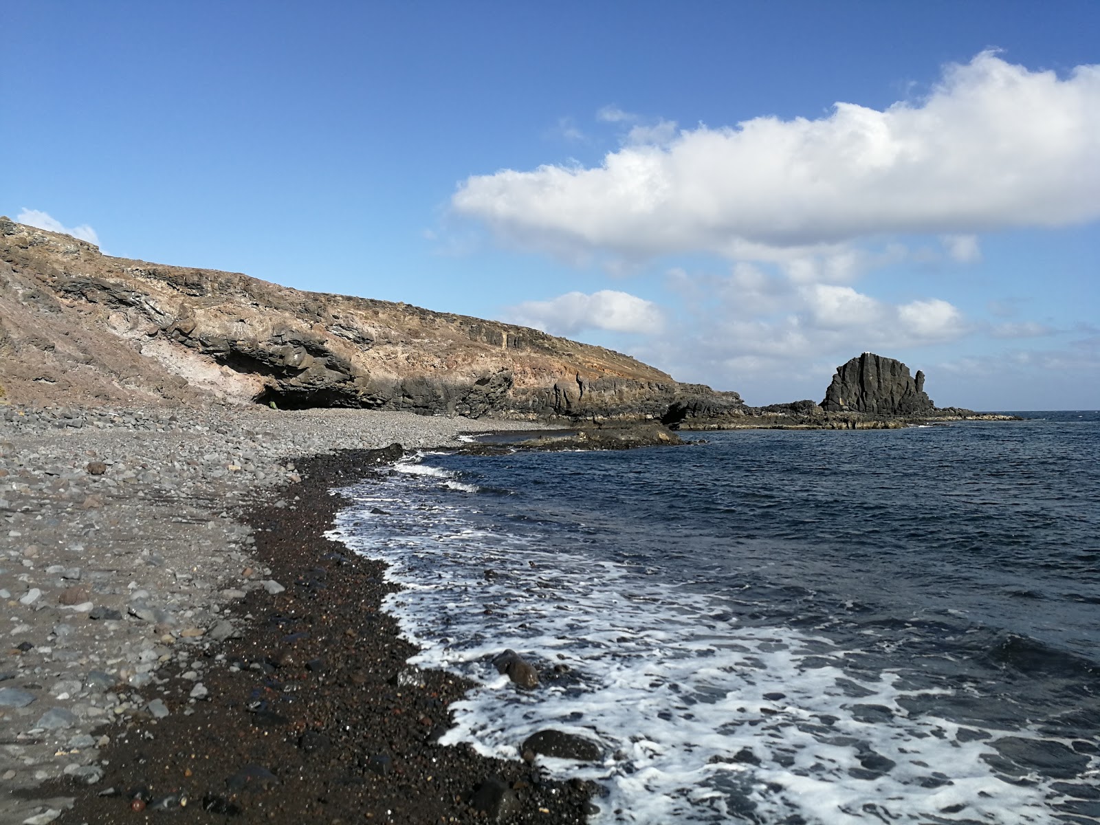 Foto de Playa Del Roque con arena gris y rocas superficie
