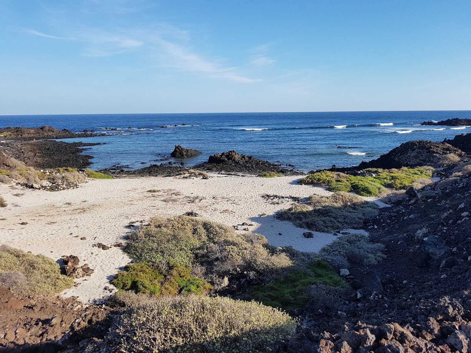 Photo of La Caleta with bright sand & rocks surface