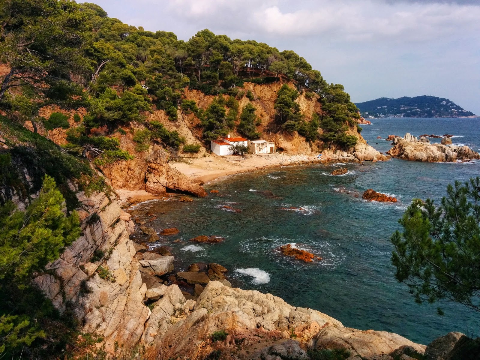 Foto di Cala del Crit con una superficie del sabbia beige e rocce
