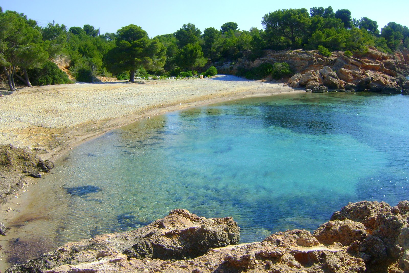 Photo of Cala Estany Podrit with black sand & pebble surface