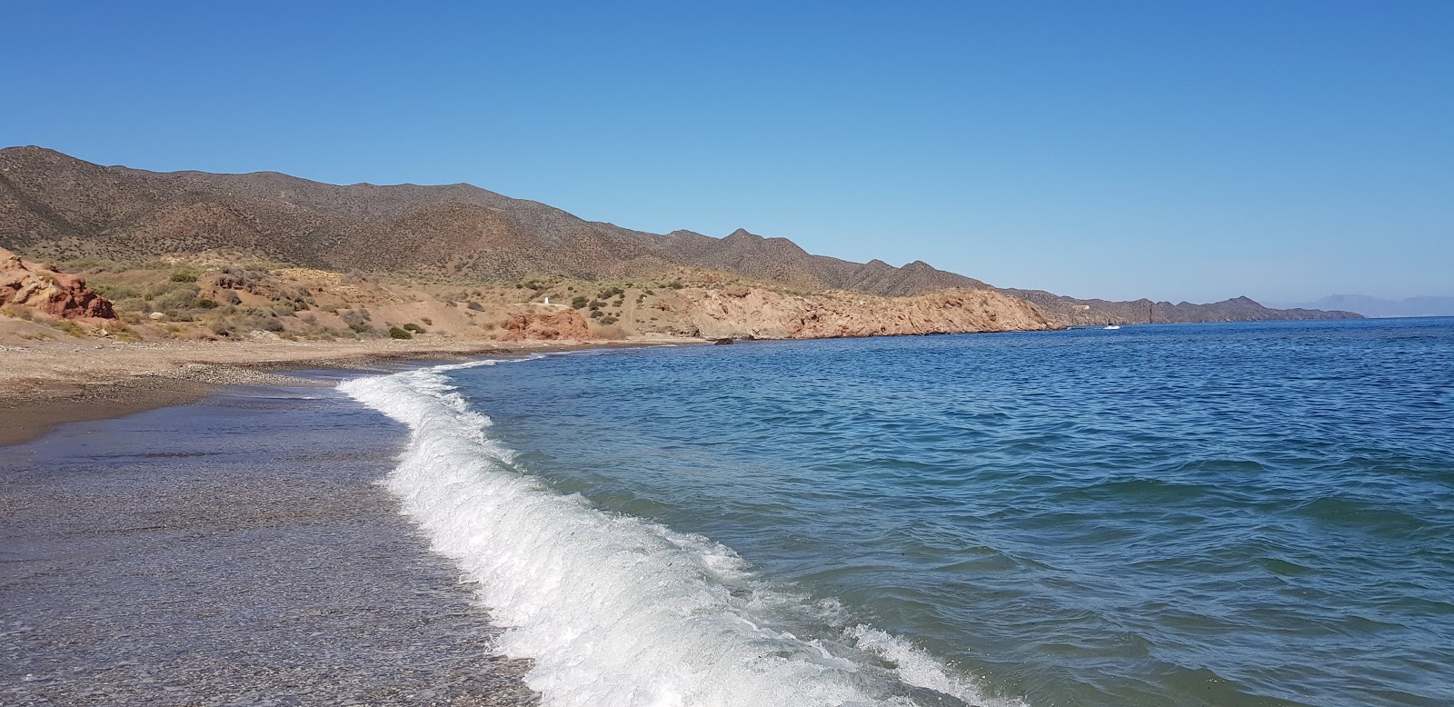 Valokuva Playa el Melarcoista. pinnalla harmaa hiekka ja kivet:n kanssa