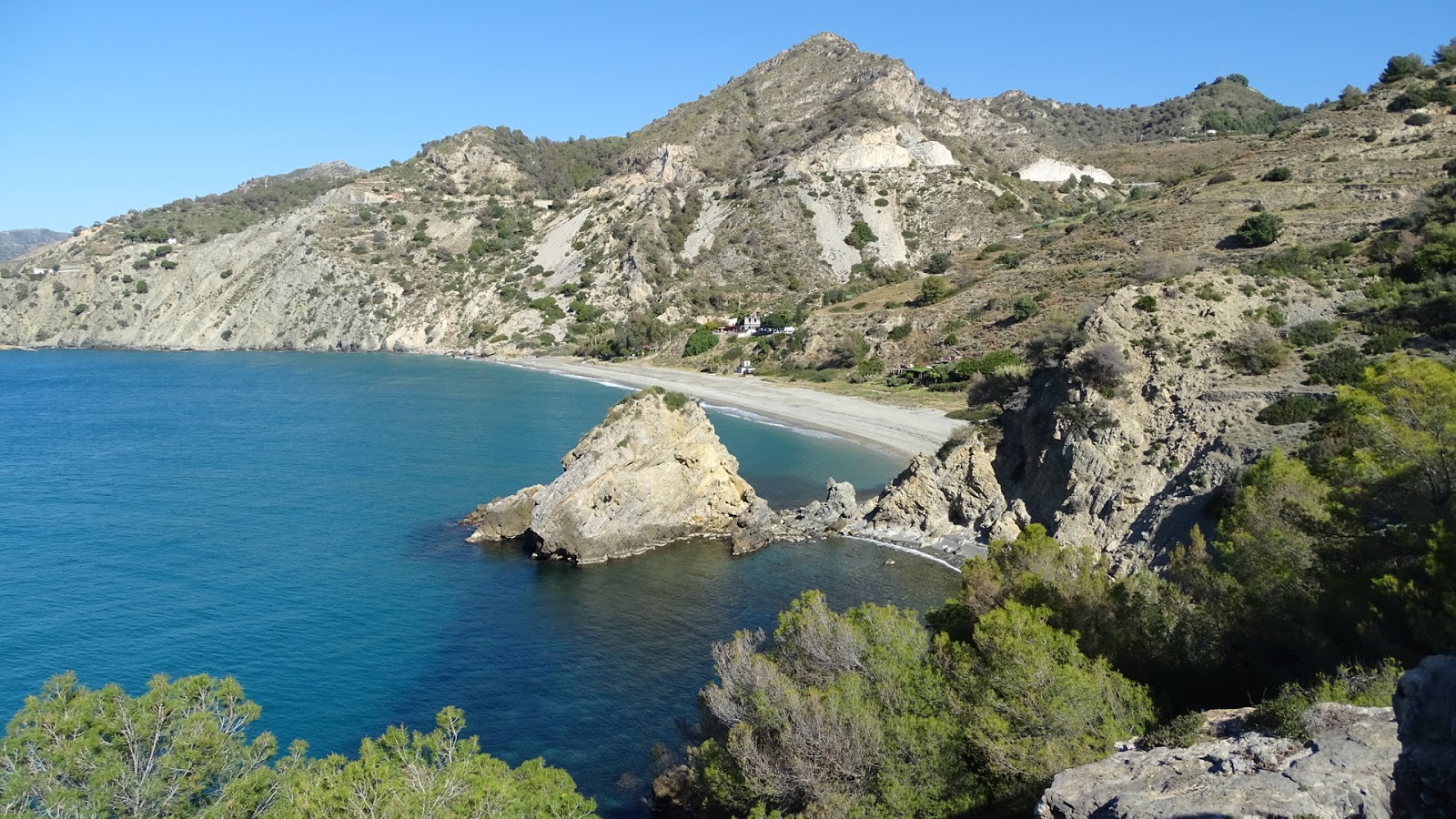 Foto di Cala del Canuelo con una superficie del piccoli ciottoli beige