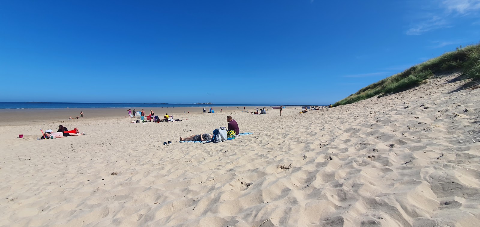Foto av Bamburgh Beach med beige sand yta
