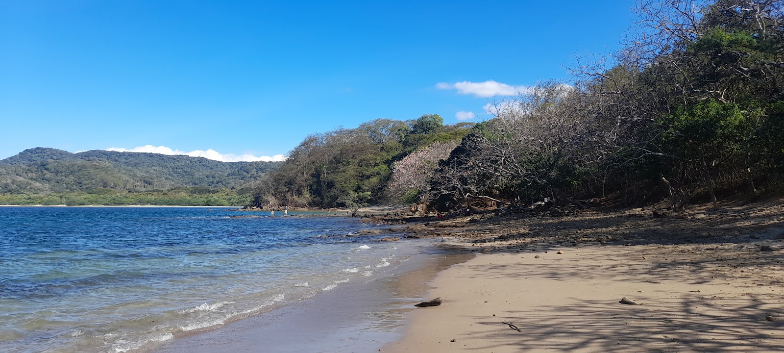 Valokuva Playa Escondidaista. pinnalla harmaa hiekka ja kivet:n kanssa