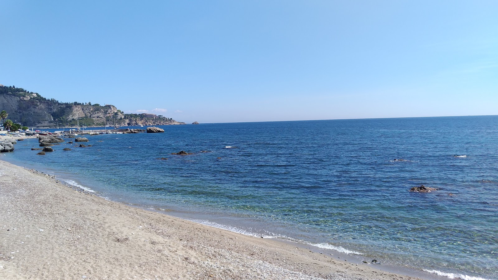 Foto av Spiaggia Giardini Naxos med musta hiekka ja kivi yta