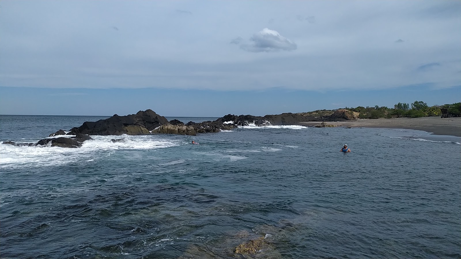 Photo of La Mona beach with gray sand &  rocks surface