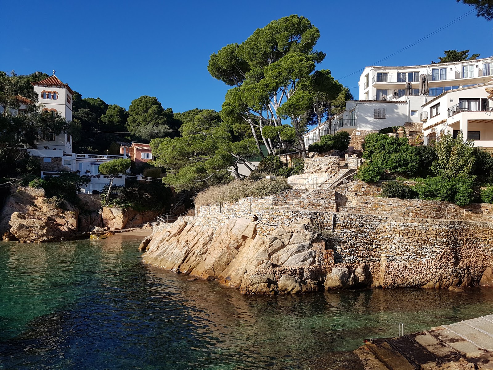 Foto van Platja de Fornells met helder zand & rotsen oppervlakte