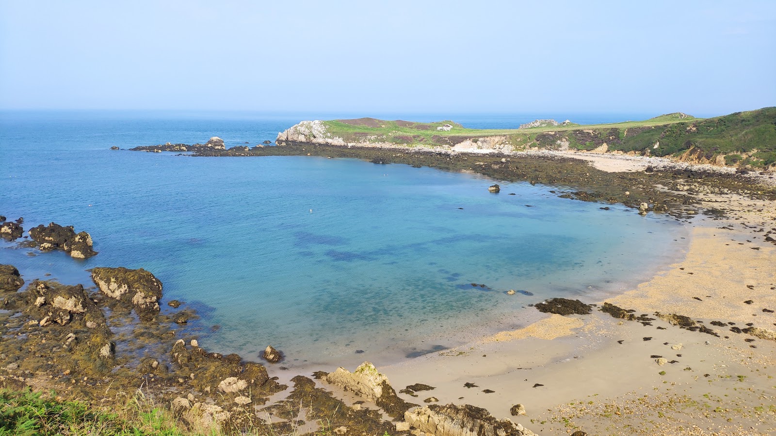 Foto av Porth Padrig med ljus sand och stenar yta