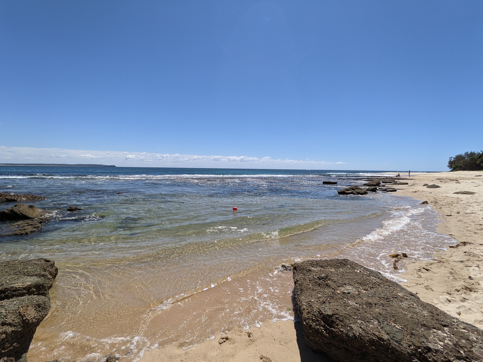 Valokuva Norah Head Lighthouse Beachista. pinnalla kirkas hiekka ja kivet:n kanssa