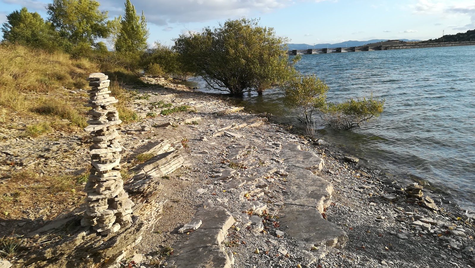 Eine ruhige Bucht an der Playa Nudista Arroiabe, die neben einem großen Stausee liegt und eine friedliche Rückzugsmöglichkeit mit Vogelbeobachtungsmöglichkeiten bietet.