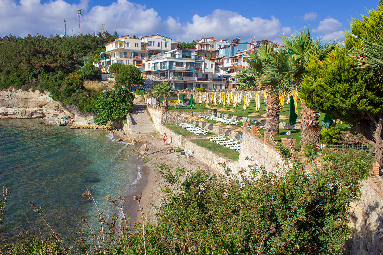 Foto av Aly Beach Club med musta hiekka ja kivi yta