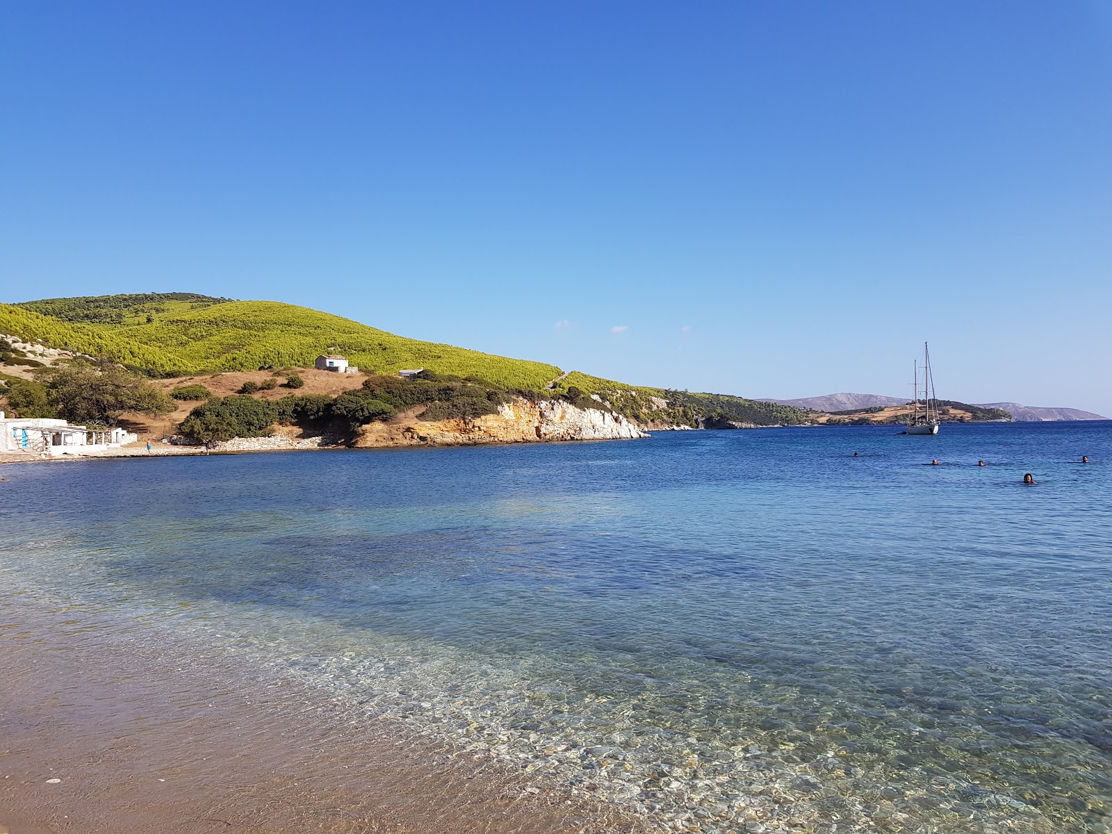 Foto av Agios Fokas beach med beige sand och stenar yta