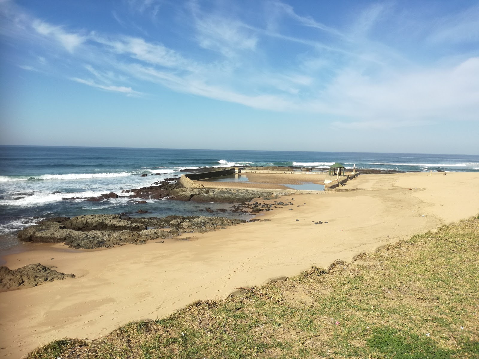 Photo of Port Shepstone beach with bright sand & rocks surface