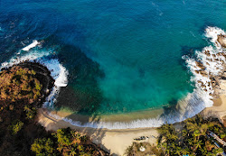 Foto von Korallenstrand von Klippen umgeben