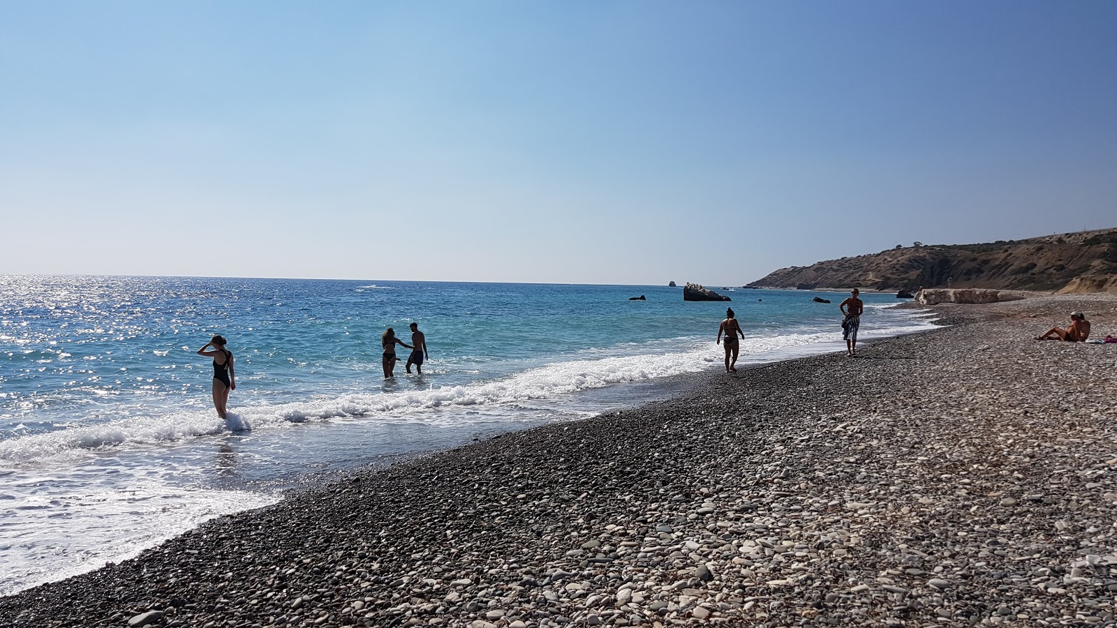 Foto av Aphrodite's rock beach omgiven av klippor
