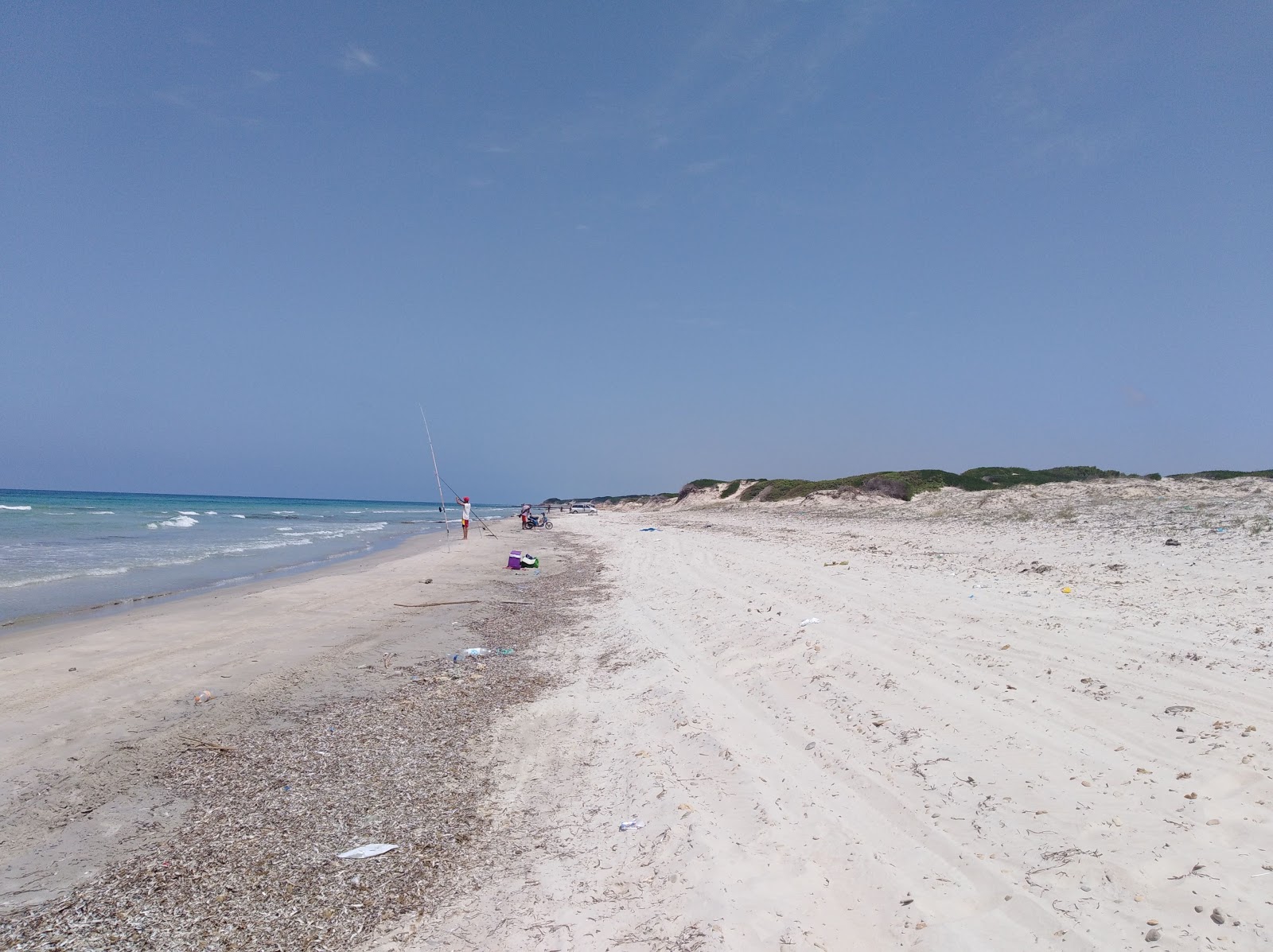 Valokuva Monotonous Beachista. pinnalla kirkas hiekka:n kanssa