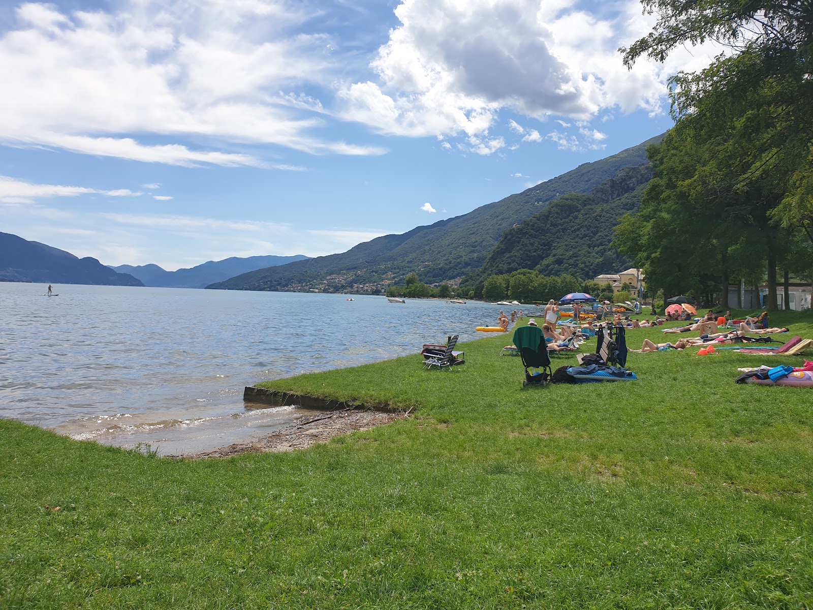Valokuva Lido di Dongo Beachista. pinnalla ruoho:n kanssa