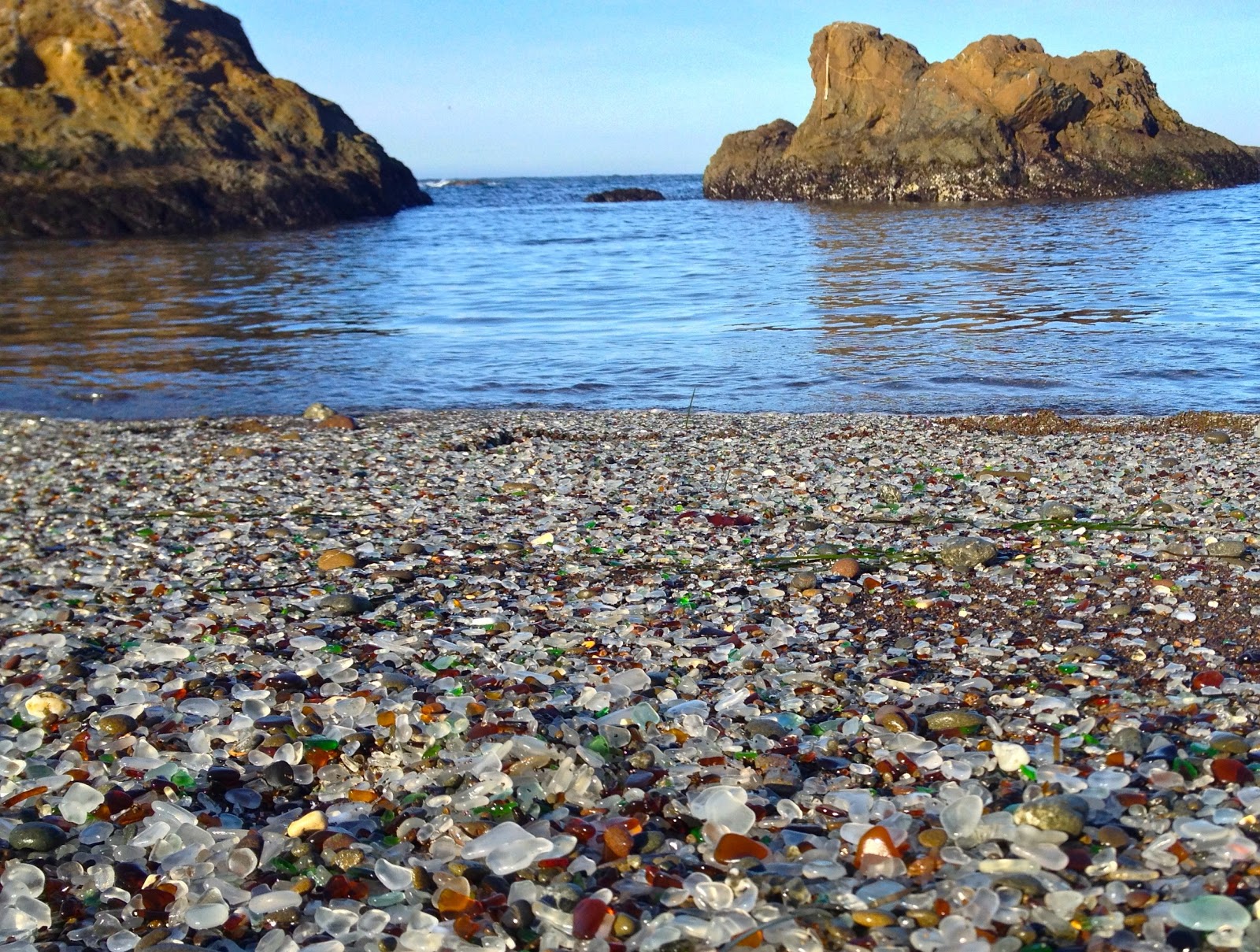 Photo of Glass Beach backed by cliffs