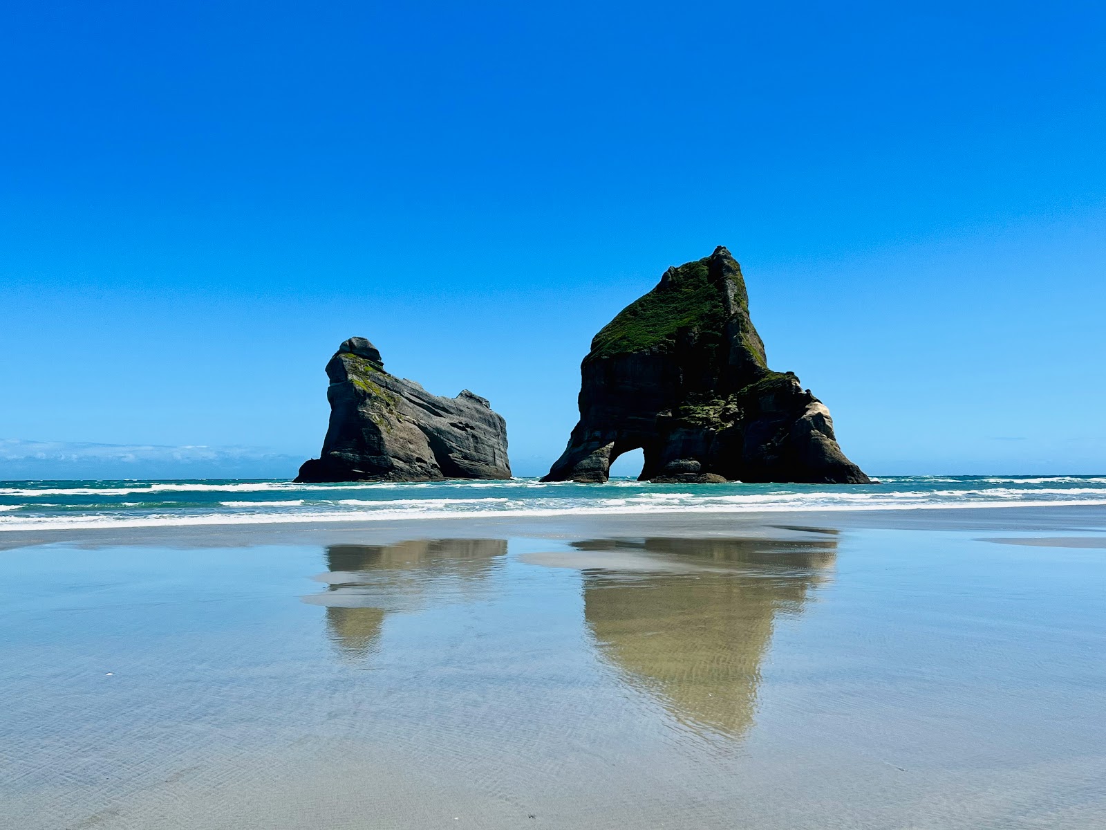 Foto av Wharariki Beach omgiven av klippor