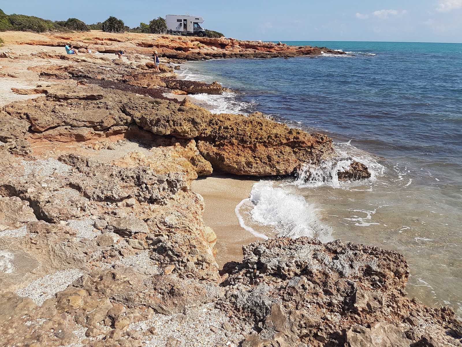 Foto di Cala l'Arjub con una superficie del sabbia marrone e rocce