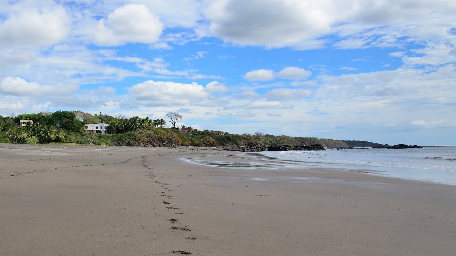 Fotografie cu Playa Azul cu o suprafață de nisip gri și roci
